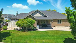 Back of property featuring board and batten siding, a patio area, a yard, and roof with shingles