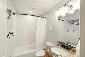Full bath with toilet, vanity, and shower / bathtub combination with curtain