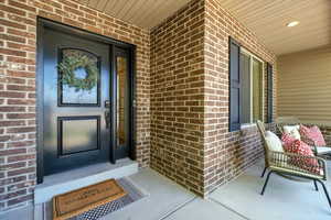 View of exterior entry with brick siding and a porch