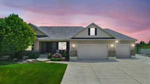 View of front of house featuring an attached garage, driveway, a lawn