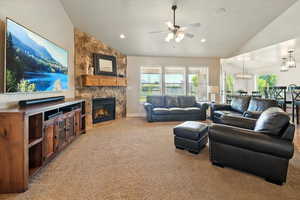 Living room with vaulted ceiling, light colored carpet, a ceiling fan, a fireplace, and recessed lighting