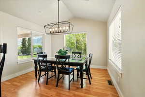 Dining area with lofted ceiling, light wood-style floors, a chandelier, and baseboards