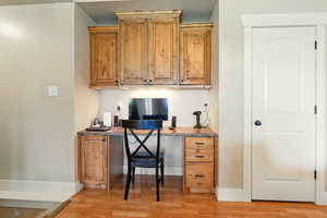 Office with light wood-style flooring, baseboards, and built in study area