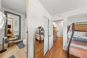 Bedroom with wood finished floors, a textured ceiling, and a closet