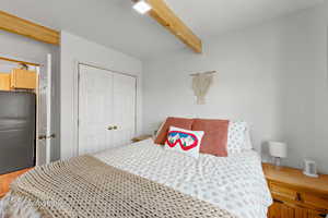 Bedroom featuring freestanding refrigerator, beam ceiling, and a closet
