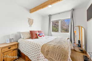 Bedroom featuring light wood finished floors and beamed ceiling