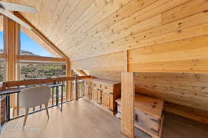 Additional living space with wooden walls, wood ceiling, and light wood finished floors