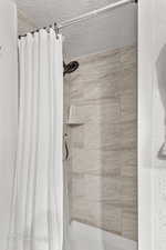 Bathroom with curtained shower and a textured ceiling