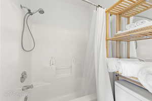 Bathroom with shower / bathtub combination with curtain and toilet
