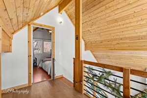 Hall featuring wooden ceiling, an upstairs landing, and hardwood / wood-style floors