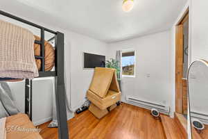 Interior space featuring a baseboard radiator, light wood-style flooring, a textured ceiling, and baseboards