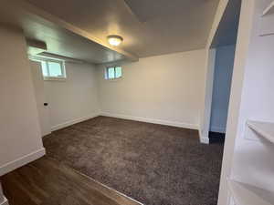 Basement with baseboards and dark colored carpet