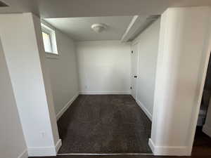 Below grade area with dark carpet and baseboards