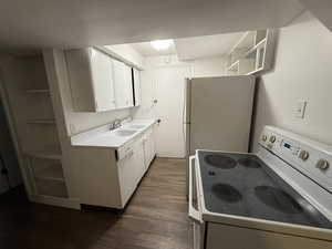 Kitchen with white appliances, a sink, open shelves, dark wood-style flooring, and white cabinetry