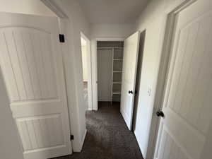 Hall featuring dark colored carpet
