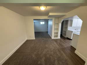 Basement featuring baseboards, dark wood-style floors, built in features, and arched walkways