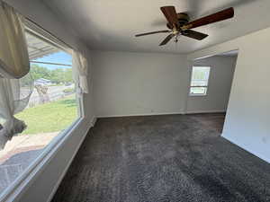 Empty room featuring carpet floors, a textured ceiling, baseboards, and ceiling fan