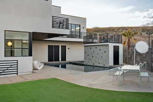 Back of house featuring a balcony, a patio area, and stucco siding
