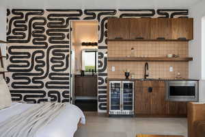 Indoor wet bar featuring wine cooler, stainless steel microwave, and decorative backsplash