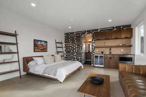 Bedroom with beverage cooler, wet bar, and recessed lighting