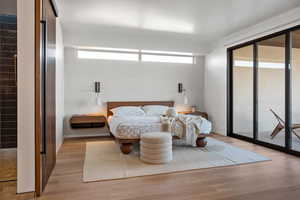 Bedroom with access to outside, light wood-type flooring, and baseboards