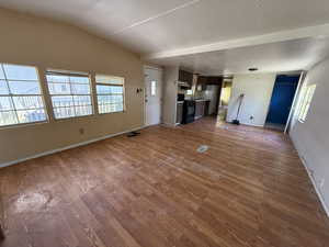 Unfurnished living room featuring wood finished floors and baseboards