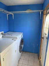 Laundry area featuring washing machine and clothes dryer and light tile patterned flooring