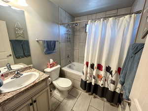 Full bathroom with toilet, tiled shower / bath combo, vanity, and tile patterned floors