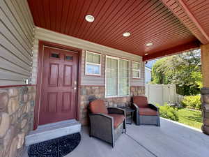 Entrance to property featuring stone siding and covered porch