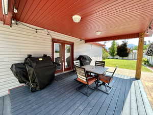 Wooden deck with french doors, outdoor dining space, and grilling area