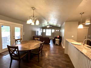 Dining area featuring vaulted ceiling, a textured ceiling, dark wood finished floors, french doors, and a ceiling fan