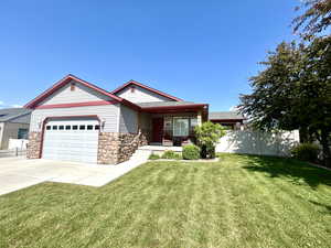 View of front of home with stone siding, an attached garage, driveway, and a porch