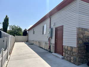 View of side of property with a fenced backyard, stone siding, and a patio area