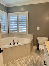 Full bathroom featuring toilet, a jetted tub, crown molding, vanity, and healthy amount of natural light