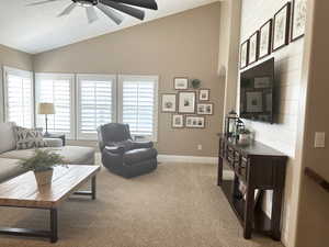 Living area featuring vaulted ceiling, ceiling fan, carpet, and baseboards