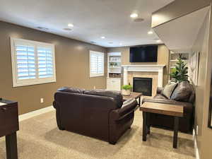 Living room with light carpet, recessed lighting, baseboards, and a tile fireplace