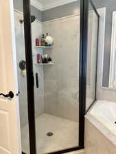 Bathroom with a shower stall, crown molding, and a bath
