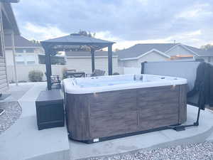 Fenced backyard featuring a hot tub, a gazebo, and a patio area