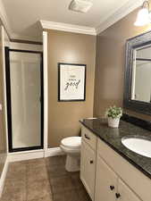 Full bath with vanity, toilet, a stall shower, ornamental molding, and a textured ceiling