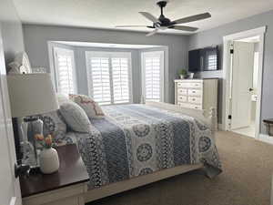 Bedroom with carpet floors, a textured ceiling, and a ceiling fan