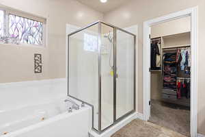 Full bathroom with a shower stall, a jetted tub, a spacious closet, and tile patterned floors