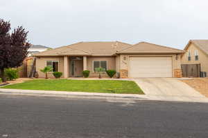 View of front of house with stucco siding, an attached garage, driveway, stone siding, and a tile roof