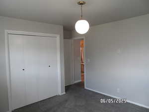 Bedroom with a closet, dark carpet, and baseboards