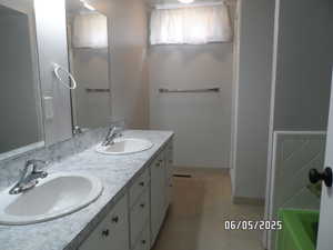 Bathroom featuring double vanity, tile patterned flooring, shower, a tub to relax in, and baseboards