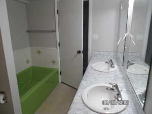 Full bath featuring a tub, double vanity, and tile patterned flooring