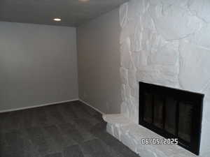 Unfurnished living room/den featuring carpet floors, a stone fireplace, baseboards, and recessed lighting