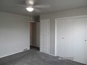 Main bedroom with dark carpet, a closet, baseboards, and ceiling fan