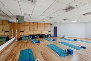 Exercise room with hardwood / wood-style flooring, wooden walls, and a paneled ceiling