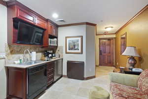 Kitchen featuring black dishwasher, stainless steel microwave, a sink, dark brown cabinets, and backsplash