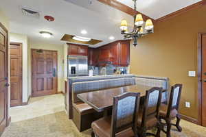 Kitchen featuring built in fridge, premium range hood, a chandelier, baseboards, and backsplash